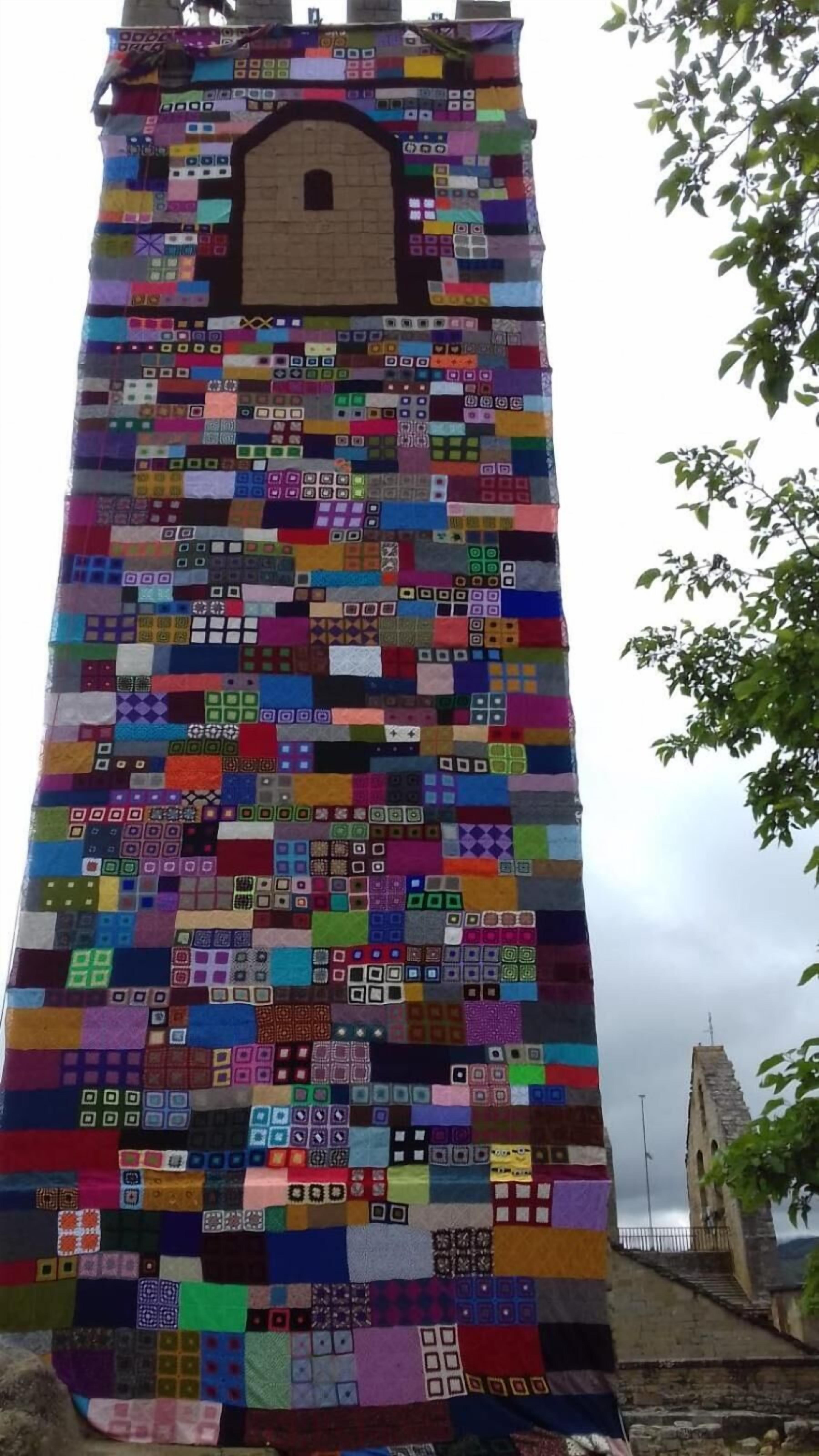 A tower with a patchwork quilt covering its exterior.