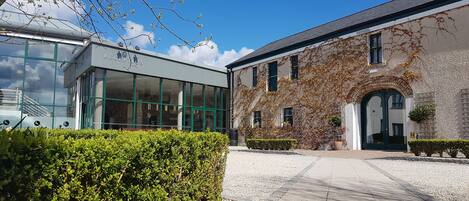 A reception area with a modern glass building and a traditional stone building with ivy.