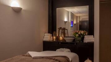 Relax in a serene spa room with a large mirror, two comfortable beds, and a cozy reading nook.