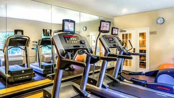 A gym with treadmills, exercise bikes, and a mirrored wall.
