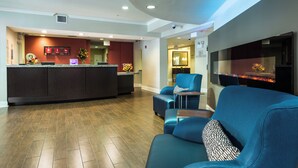 Un hall d’hôtel comprenant un comptoir d’accueil, un espace salon et une cheminée.