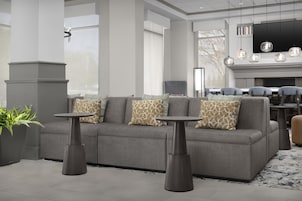 A modern living room with a grey sectional sofa, two round side tables, and a fireplace with bookshelves.
