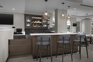 A modern kitchen with a bar area, bar stools, and a television mounted on the wall.