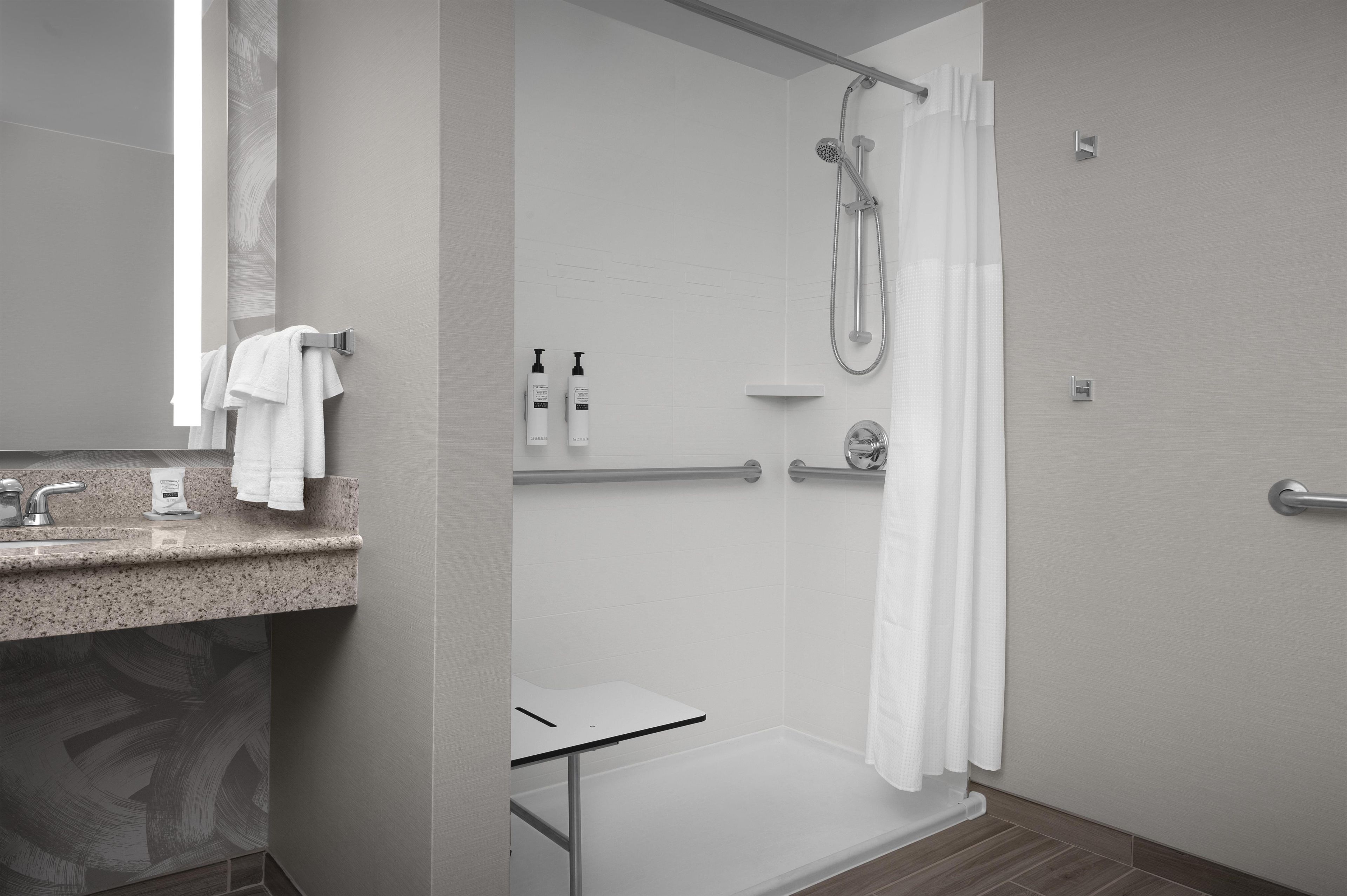 A modern bathroom with a shower, a toilet, and a sink with a towel rack.