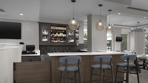 A modern bar area with a wooden counter, bar stools, and a wine display. - Hilton Garden Inn Annapolis (Annapolis)