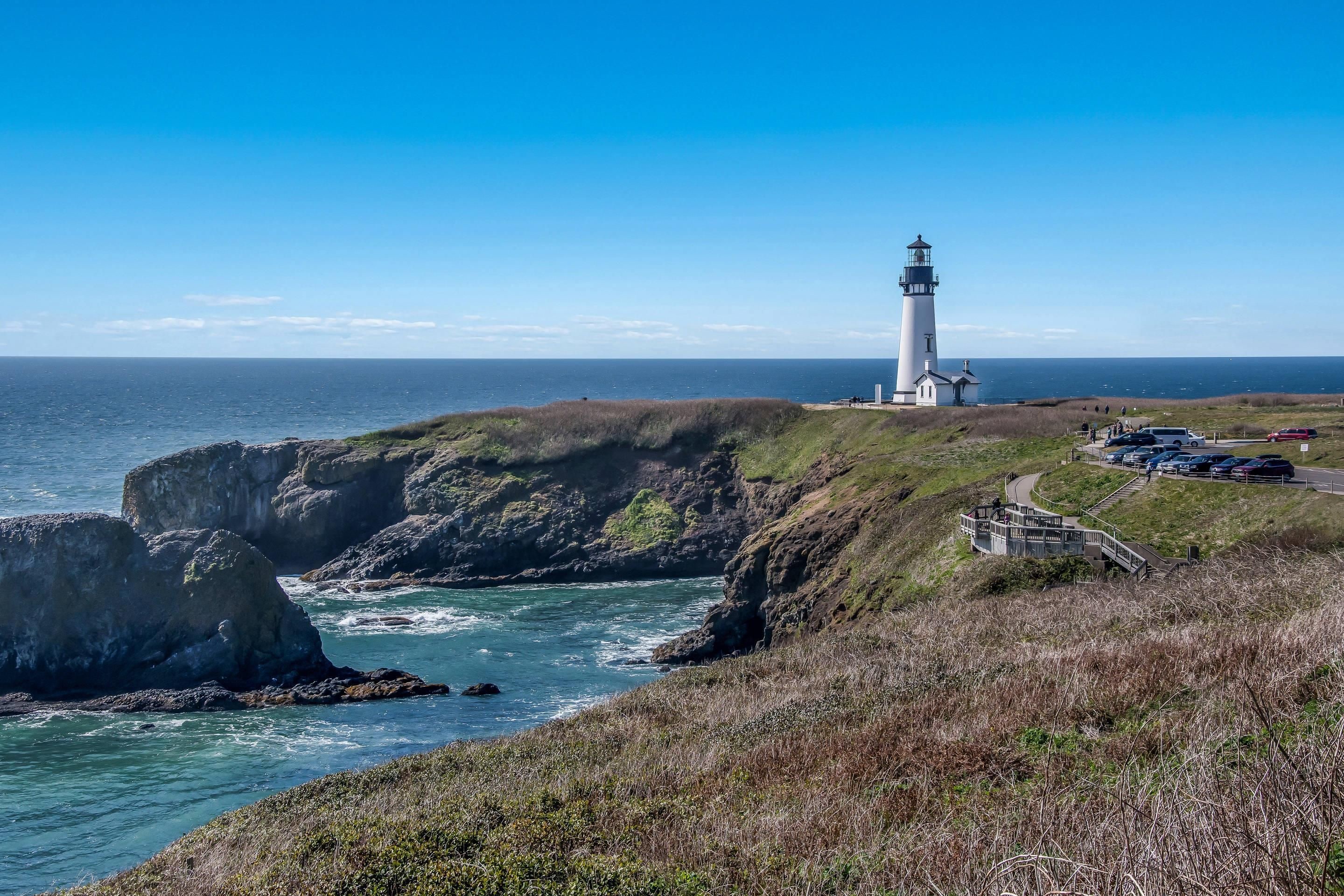 Un faro en un acantilado con vistas al mar, bajo un cielo despejado.