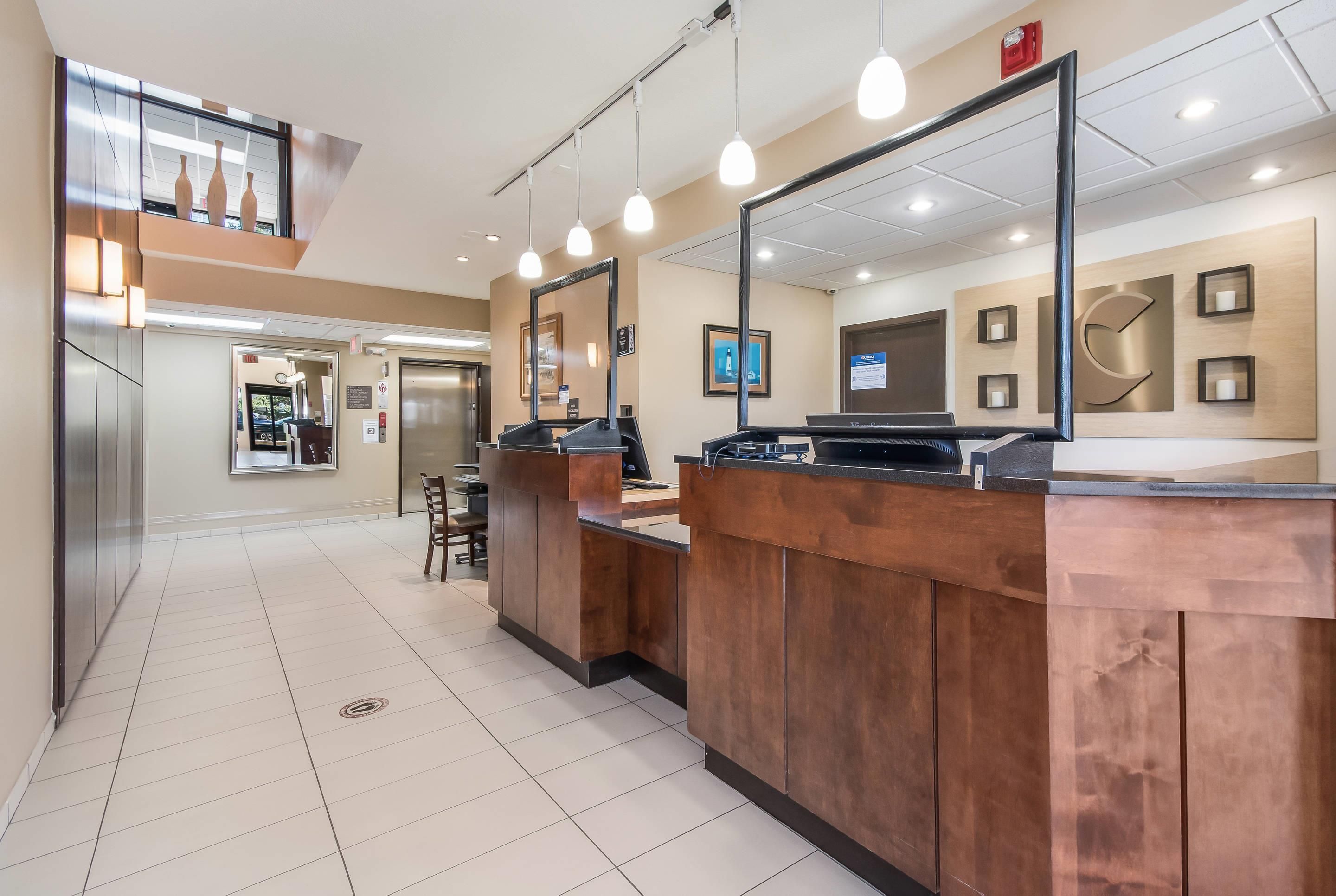 A hotel lobby with a reception desk, a mirror, and a view of the elevator area.