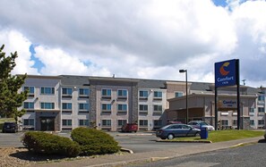 A Comfort Inn hotel with a parking lot, multiple cars, and a clear sky. - Comfort Inn Newport (Newport)
