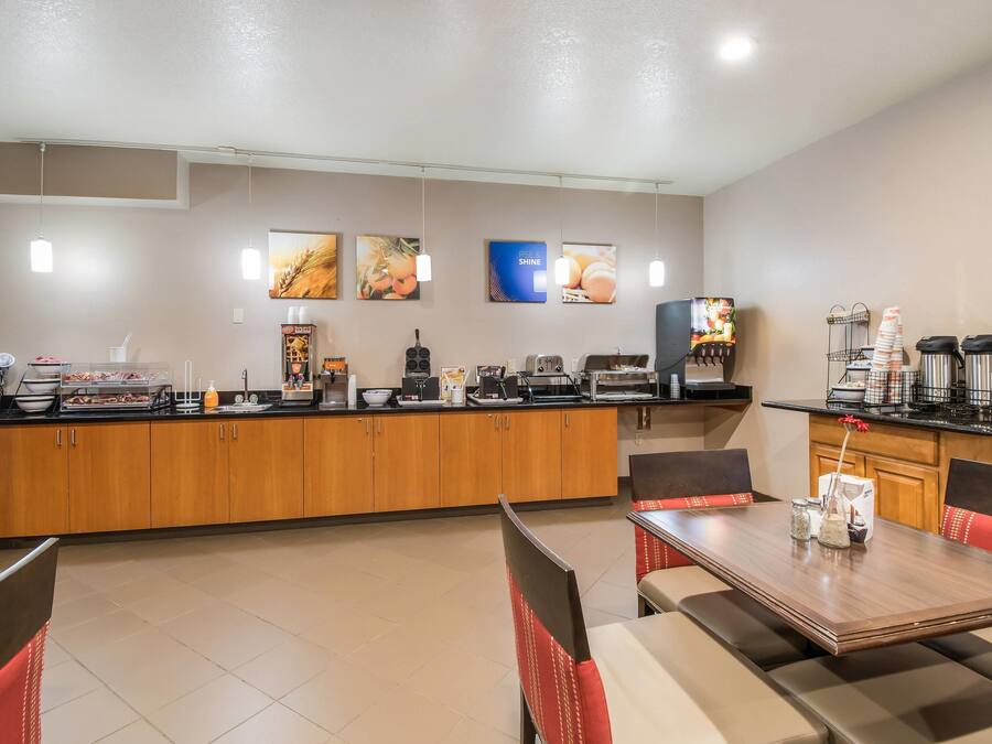 A hotel breakfast area with a counter, seating, and various food and beverage stations.