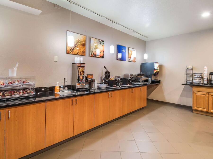 A hotel kitchen with wooden cabinets, a coffee station, and a buffet area with food items.