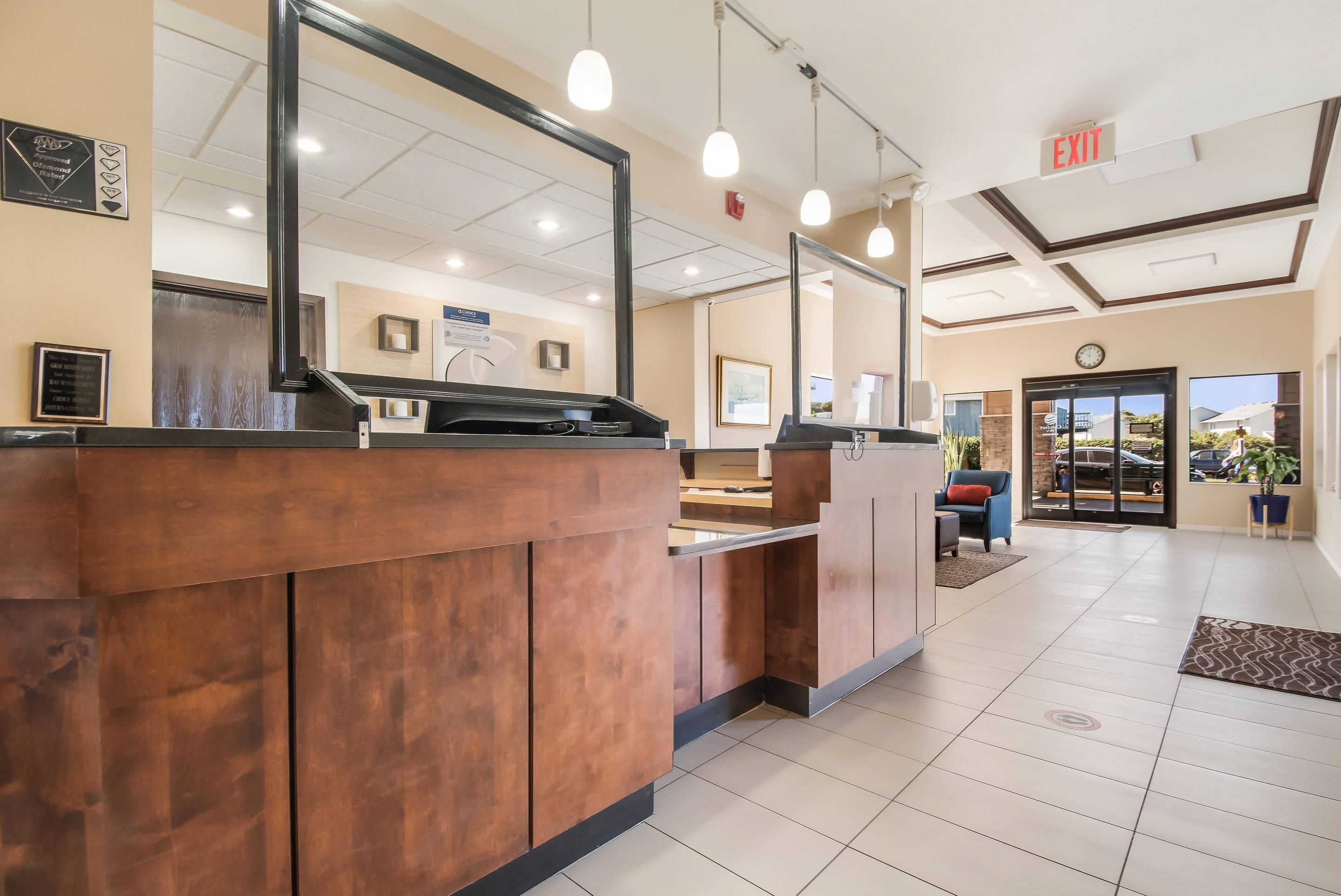 A reception area with a counter, a large mirror, and a clock on the wall.