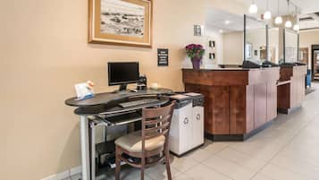A reception desk with a computer, a chair, and a framed picture on the wall.