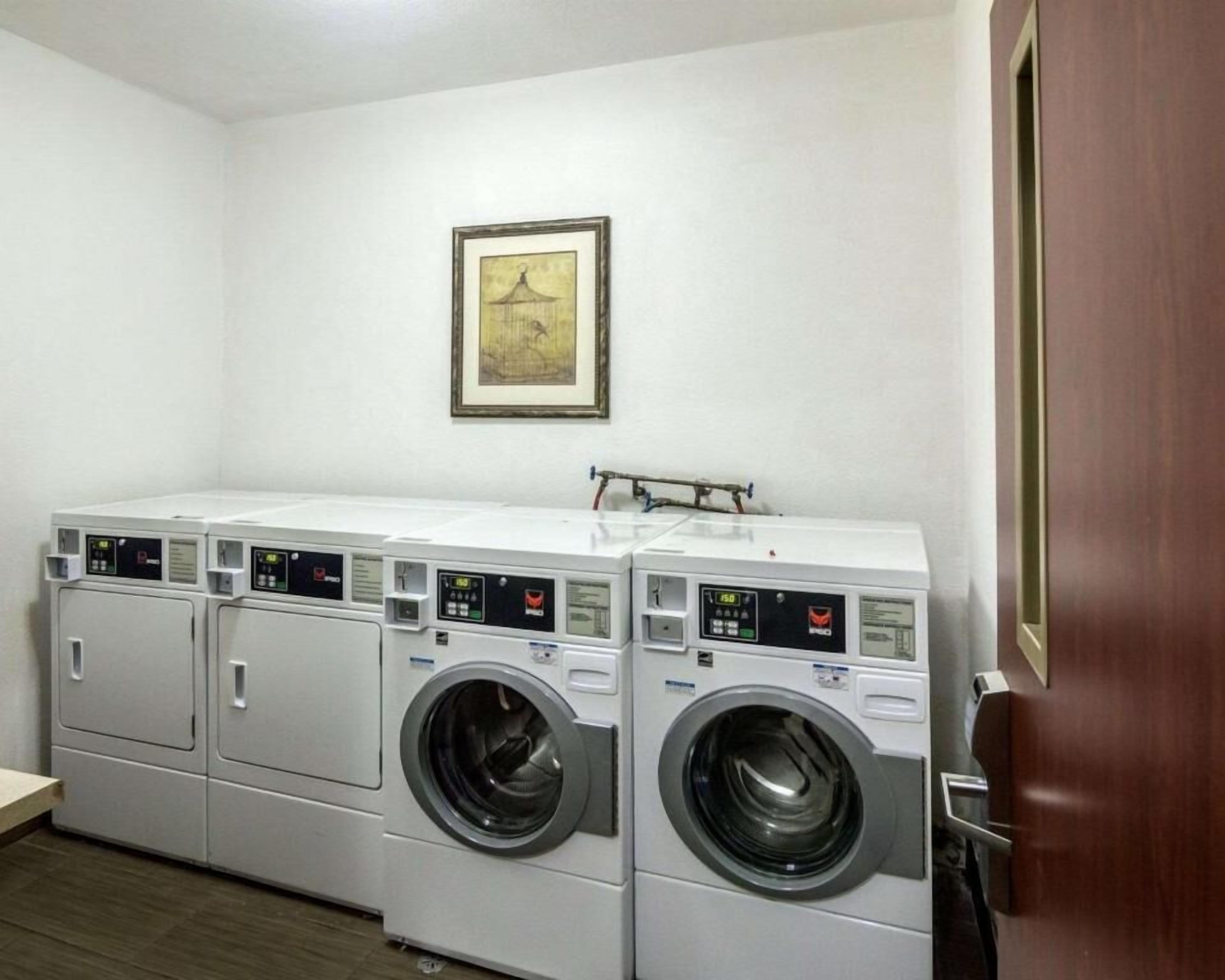 A laundry room with four stacked washing machines and a single dryer.