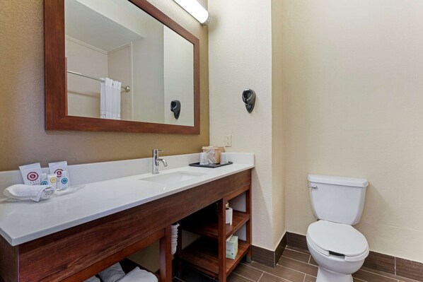 A bathroom with a wooden vanity, a white sink, a mirror, a toilet, and a towel rack.