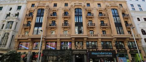Un edificio de varios pisos con detalles arquitectónicos ornamentados, incluyendo balcones y ventanas amplias.