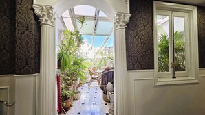 A room with a tiled floor, a window, and a view of an outdoor area with plants.
