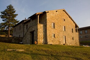 Um edifício de pedra com telhado inclinado, uma porta e janelas.