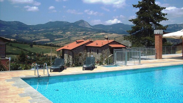A swimming pool with lounge chairs and a view of mountains. - Hotel Gli Orzali (Firenzuola)