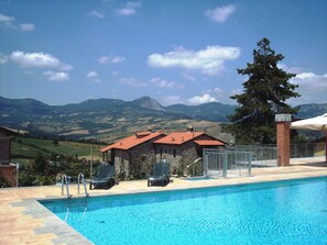 Una piscina con sillones de descanso y vistas a montañas.