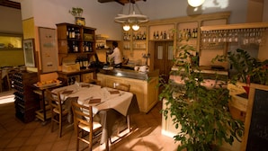 A cozy restaurant interior with a bar area, wooden furniture, and a variety of bottles and glasses on shelves. - Hotel Gli Orzali (Firenzuola)