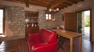 Una habitación acogedora con pared de piedra, muebles de madera y un sofá de cuero rojo.