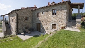 A stone building with a patio, outdoor seating, and a staircase leading to an upper level. - Hotel Gli Orzali (Firenzuola)