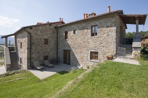 Un edificio de piedra con un patio, asientos al aire libre y una escalera que conduce a un nivel superior.
