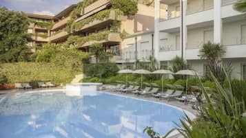 Alberca al aire libre, sombrillas en la alberca y camastros