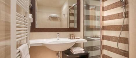 A modern bathroom with a large mirror, white sink, and a glass-enclosed shower.