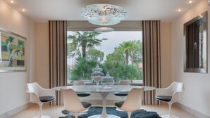 Een moderne eetruimte met een glazen tafel, witte stoelen en een decoratief middelpunt.