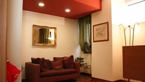 Een woonkamer met een bruine bank, een spiegel, een lijst met een afbeelding en een lamp.