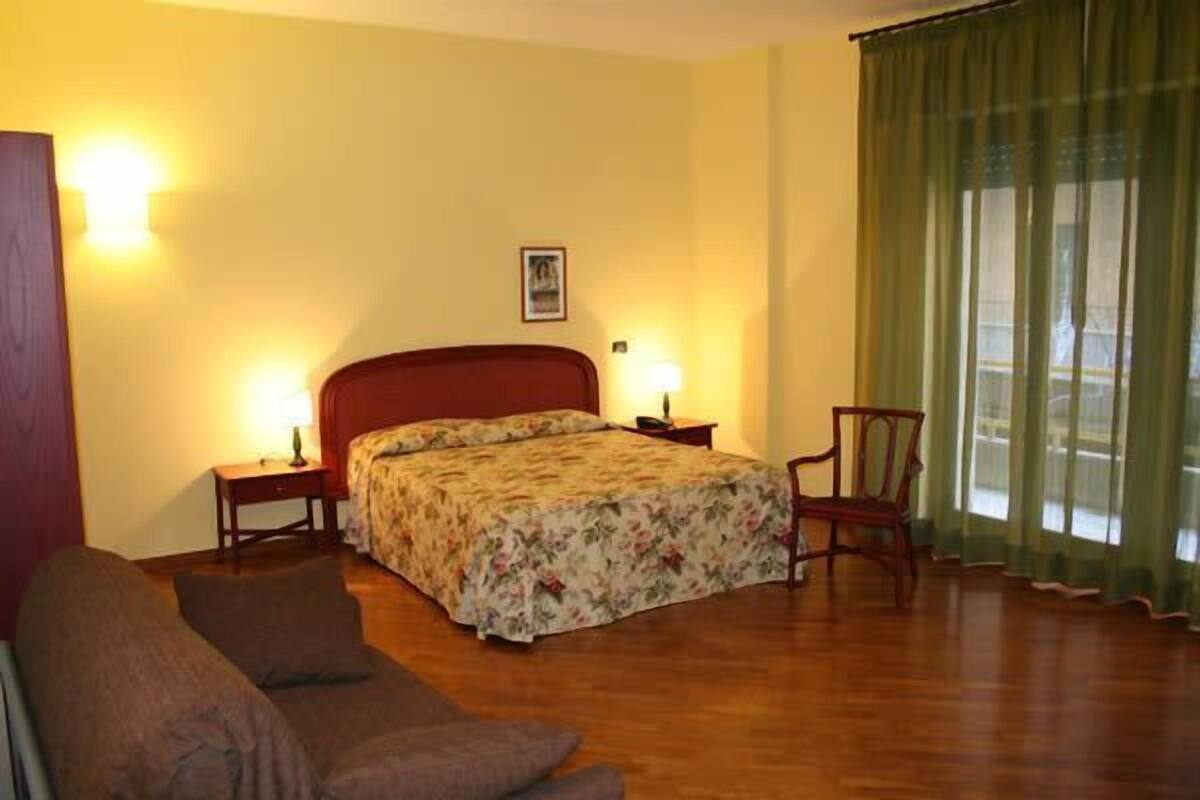 Ein Hotelzimmer mit Bett, Stuhl, Nachttisch und Lampe.