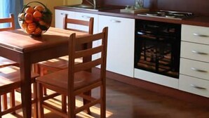 Een moderne keuken met witte kasten, een houten eettafel en een fruitschaal.