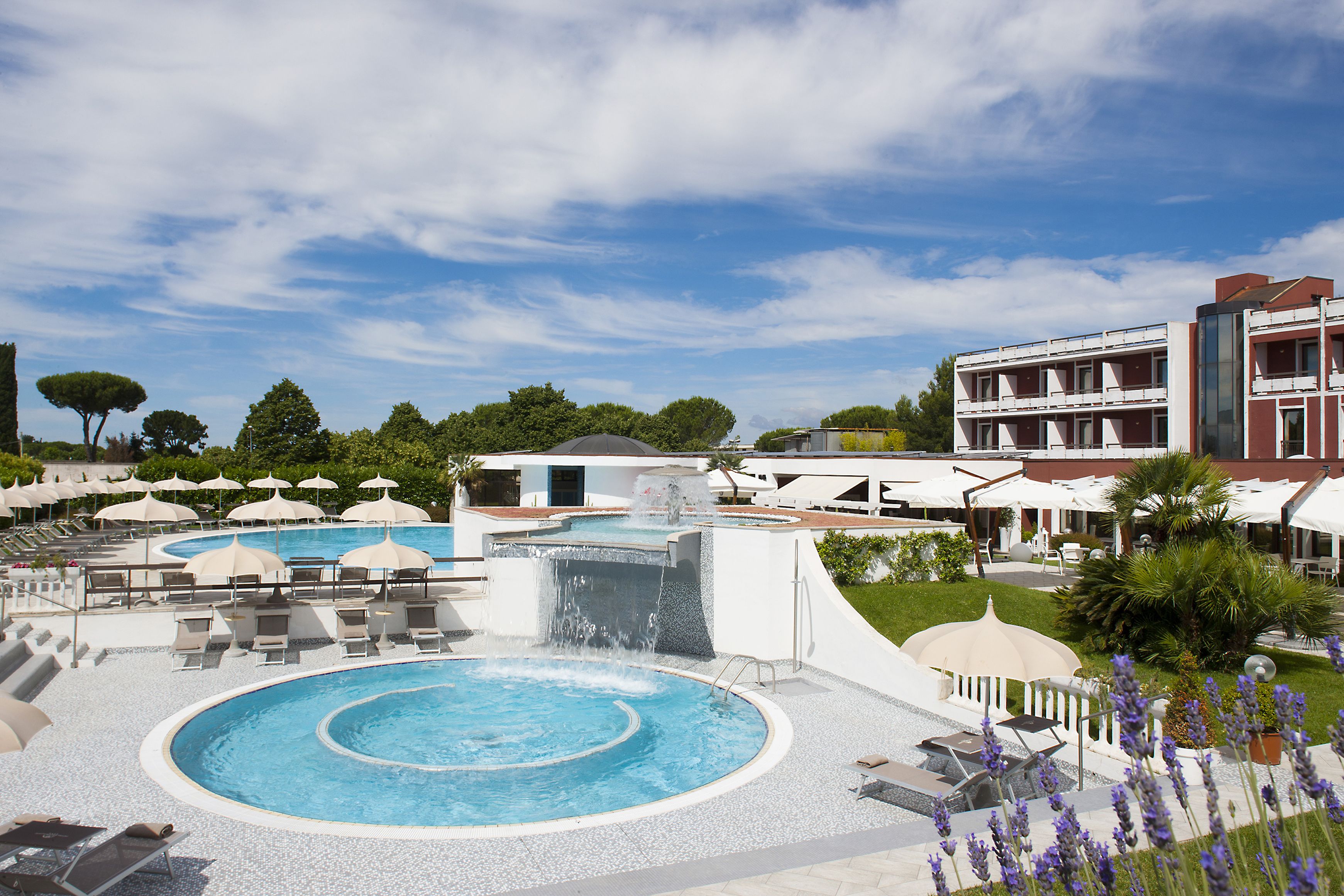 Un resort con una piscina grande, sillas de descanso y un edificio con varios balcones.