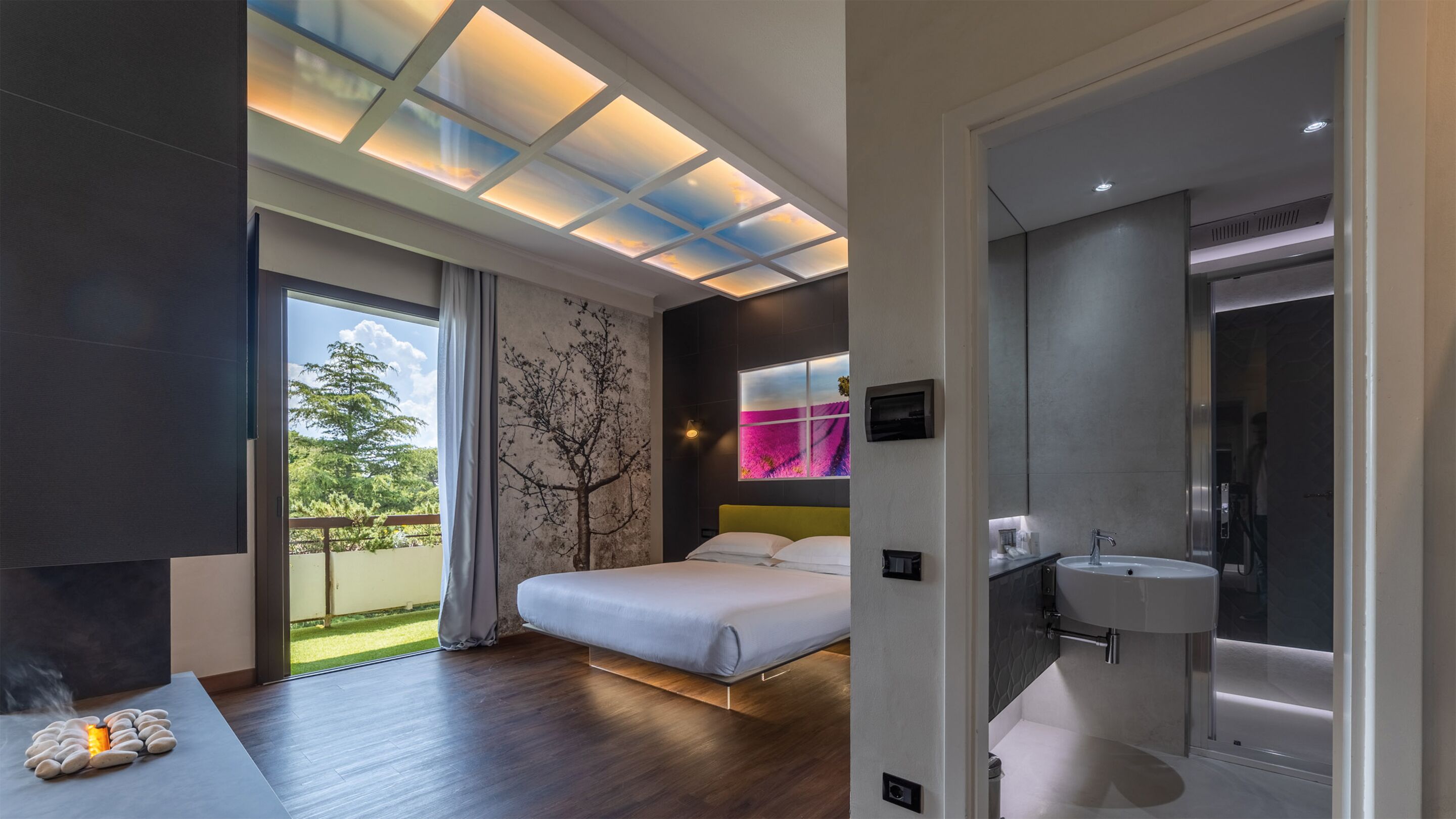 Un dormitorio moderno con una cama grande, un tragaluz y vistas a zonas verdes.