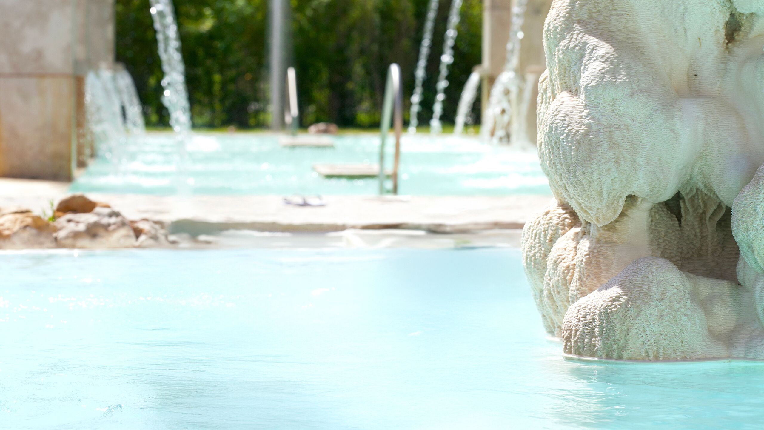 Una piscina con acqua cristallina e una formazione rocciosa in primo piano.