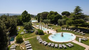 Un resort con múltiples piscinas, tumbonas y abundante vegetación.