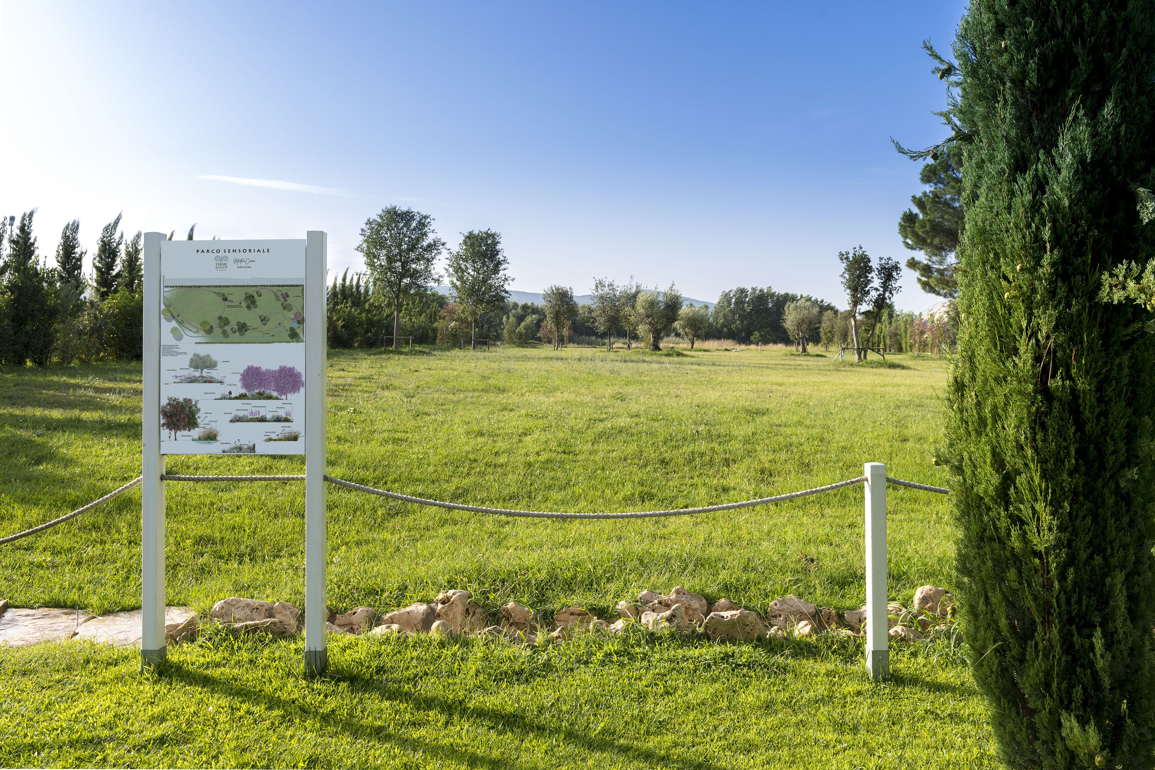 A grassy field with a signboard and a rope barrier.