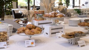 A buffet with various pastries and baked goods, including croissants and muffins, displayed on white stands with labels. - Hotel Salus Terme - Adults Only (Viterbo)