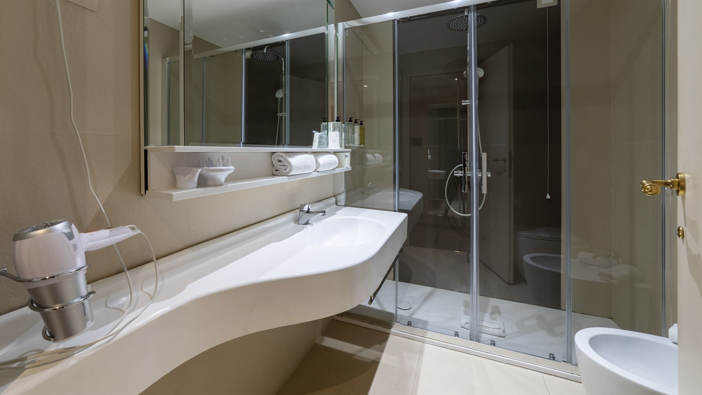 Une salle de bain moderne avec un grand lavabo blanc, une douche en verre et des toilettes.