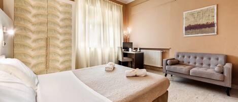 A hotel room with a bed, a sofa, a desk, and a large window with curtains.