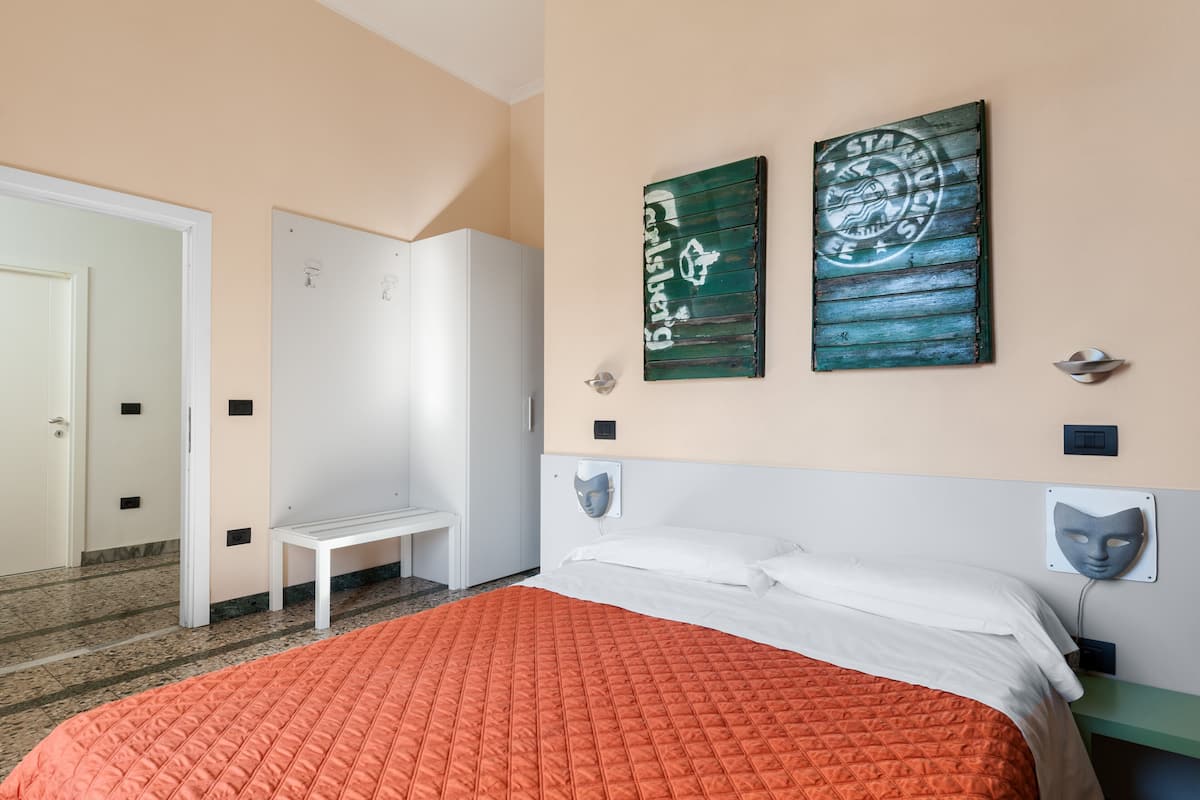 A bedroom with a bed, a bench, and two wall decorations.
