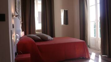 Una camera da letto con un letto, un comodino, uno specchio e una finestra con tende.