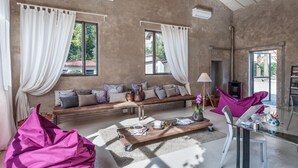 A spacious living area with a large sofa set, a coffee table, and a dining table. There are large windows with curtains, a ceiling light fixture, and a view of the outdoors. - Lucca In Villa Elisa & Gentucca (Lucca)