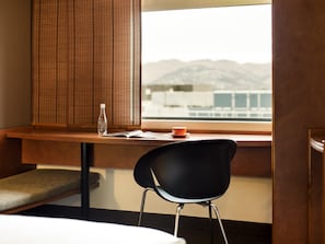A hotel room with a wooden desk, a black chair, a bottle of water, and a cup on the windowsill. - ibis Christchurch (Christchurch)