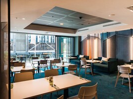 Un área de comedor moderna con mesas y sillas, vistas al exterior y un diseño de techo singular.