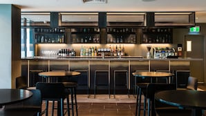 Eine Bar mit verschiedenen Sitzgelegenheiten, einer gut sortierten Spirituosenregal und einem sichtbaren Notausgang.