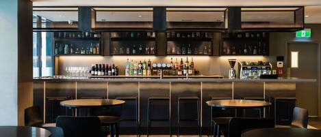 A bar area with multiple seating options, a well-stocked liquor shelf, and a visible exit sign.