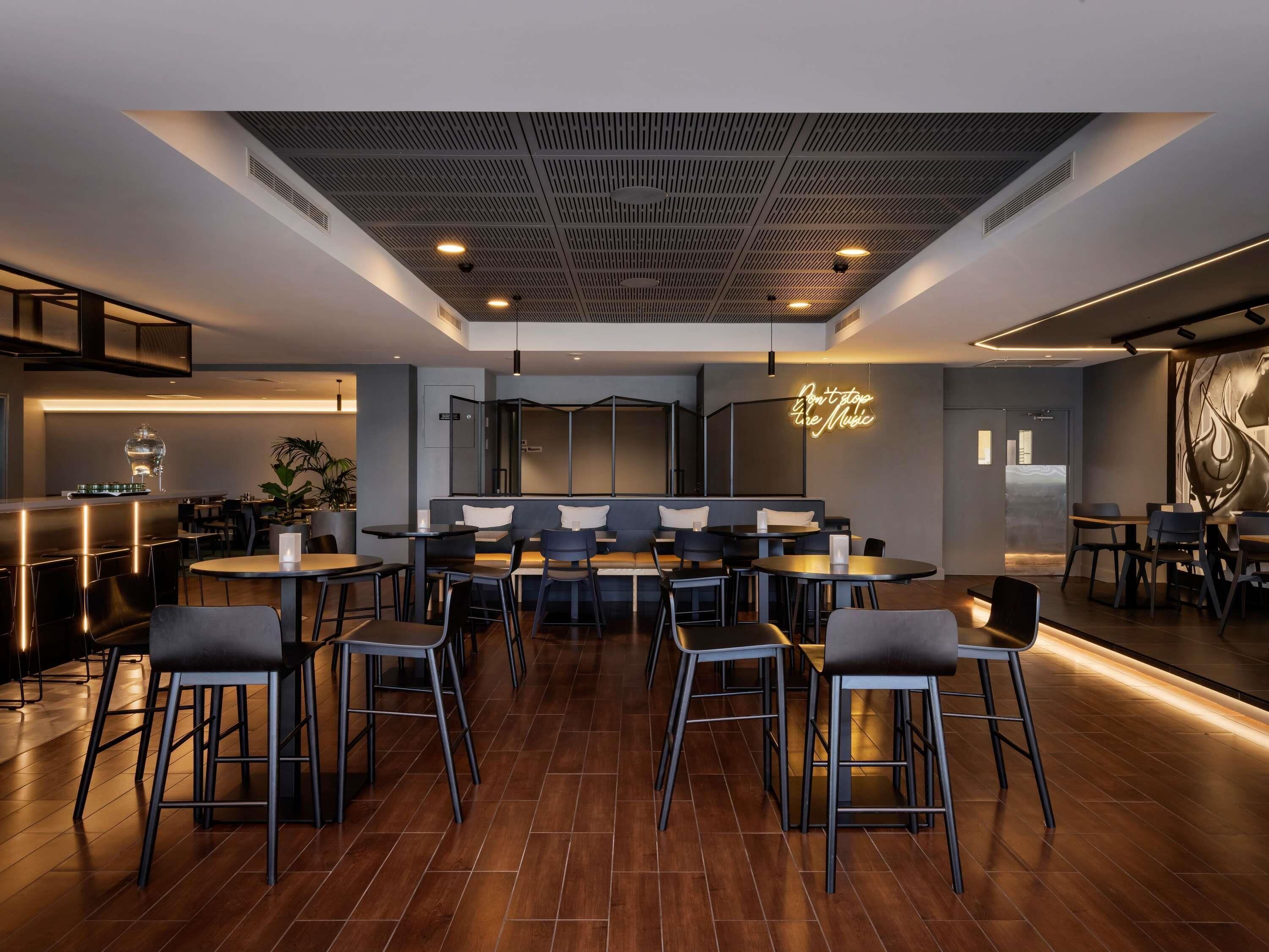 A modern restaurant with a central seating area, a bar on the left, and a counter on the right.