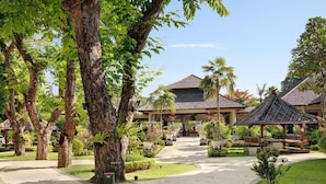 A resort with a central building, a covered walkway, and surrounding lush greenery. - Novotel Bali Nusa Dua (Nusa Dua)
